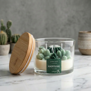 Duftkerze im Glas mit Kaktus-Design, „Kacktusse“ Schriftzug und Holzdeckel auf heller Marmoroberfläche