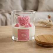 Handgegossene Duftkerze im Glas („Lovely Heart“) mit Herzmotiv in Rosa und dekorativer, minimalistischer Umgebung